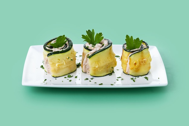Rollos de calabacín a la parrilla con atún y queso crema sobre fondo verde
