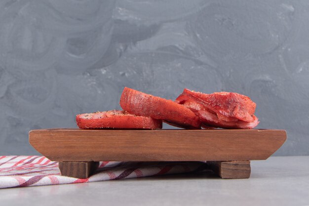 Rollos de carne ahumada sobre tabla de madera.