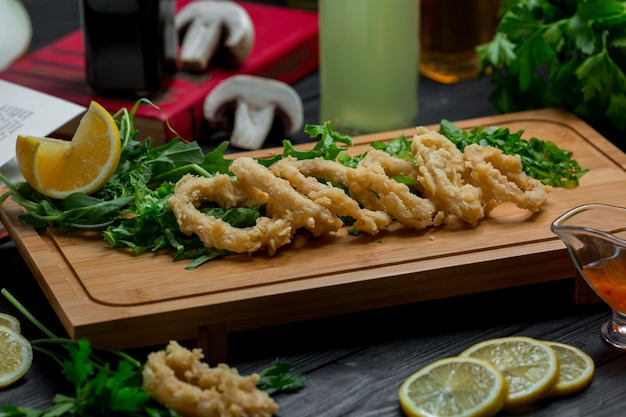 Rollos de cebolla asada con hierbas frescas y rodajas de limón.