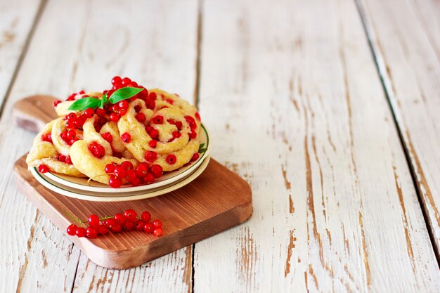 Rollos de galleta de requesón con grosellas rojas en plato de cerámica con té o café de cerámica vintage, hora del té, desayuno, dulces de verano