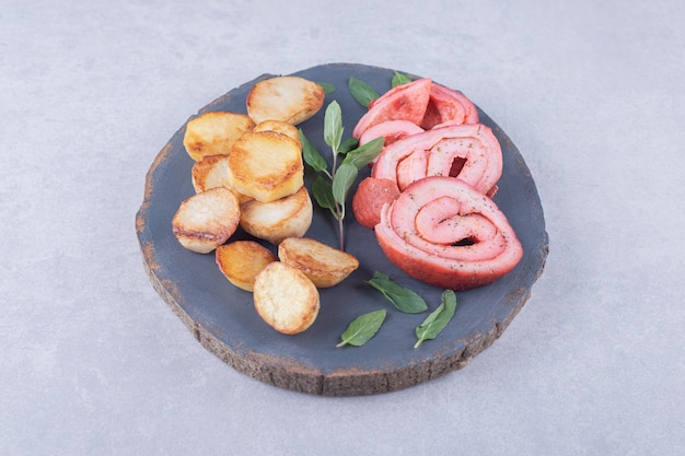 Rollos de jamón y patatas fritas sobre pieza de madera.