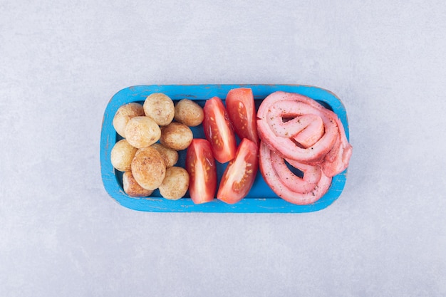 Rollos de jamón, tomates y patatas fritas en placa azul.