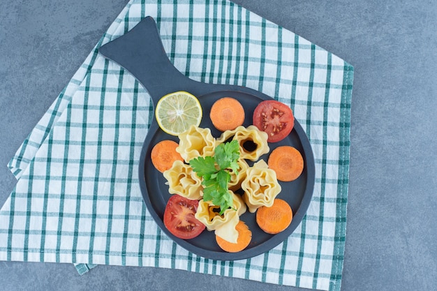 Rollos de masa hervida y verduras en tablero oscuro.