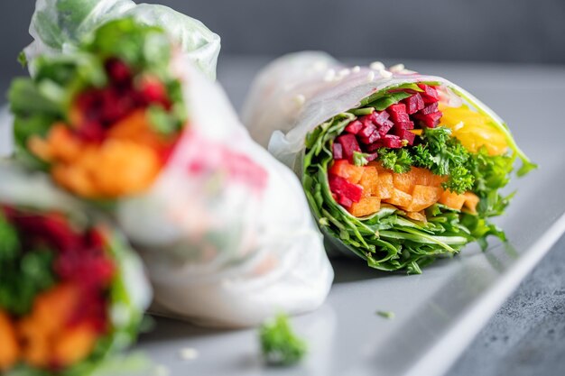 Rollos de papel de arroz vegano con verduras y sésamo servidos en un plato listo para comer