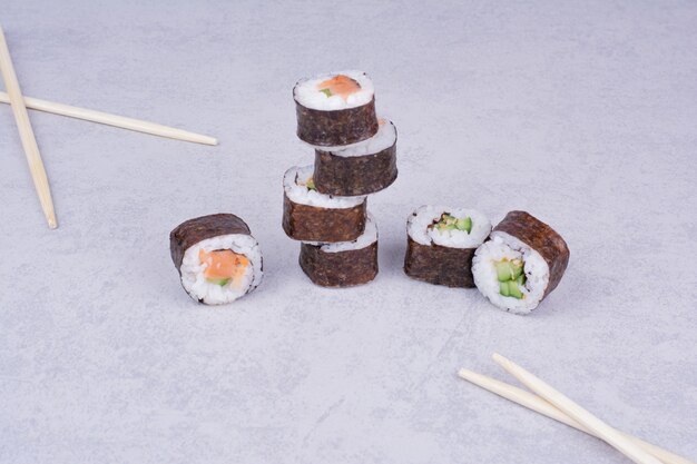 Rollos de sake maki sobre fondo gris con palillos