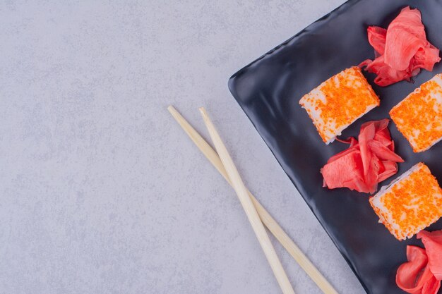 Rollos de salmón Philadelphia con jengibre rojo en una bandeja de cerámica