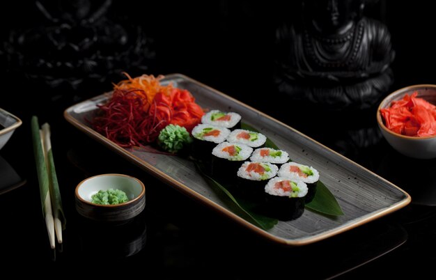 Rollos de sushi con aperitivos en un plato gris