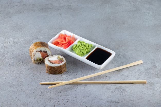 Rollos de sushi con atún, wasabi, jengibre y salsa de soja sobre fondo de piedra.