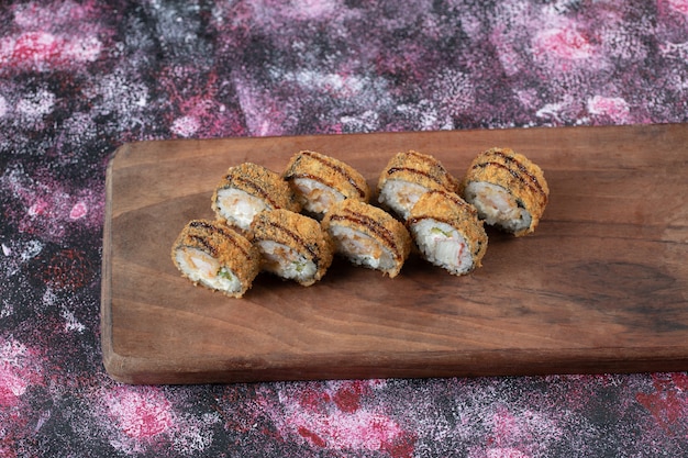 Foto gratuita rollos de sushi caliente con queso crema sobre una tabla de madera.