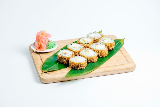 Rollos de sushi caliente servido en hojas sobre tablero de madera en fondo blanco.