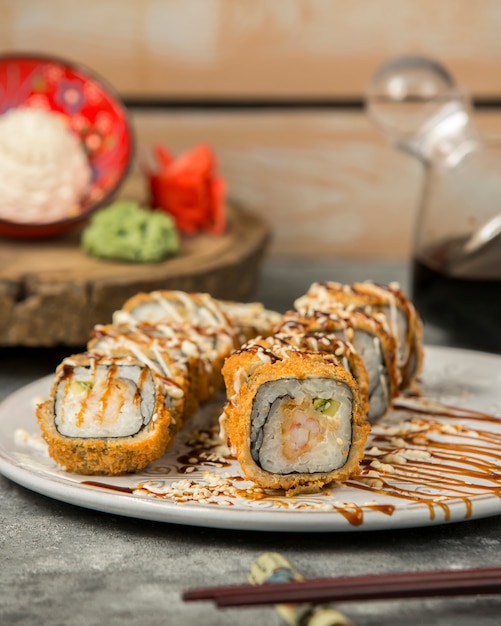 Rollos de sushi calientes con camarones y pepino con salsa y sésamo