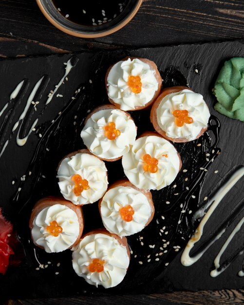 Rollos de sushi con crema y caviar rojo servidos con jengibre y wasabi