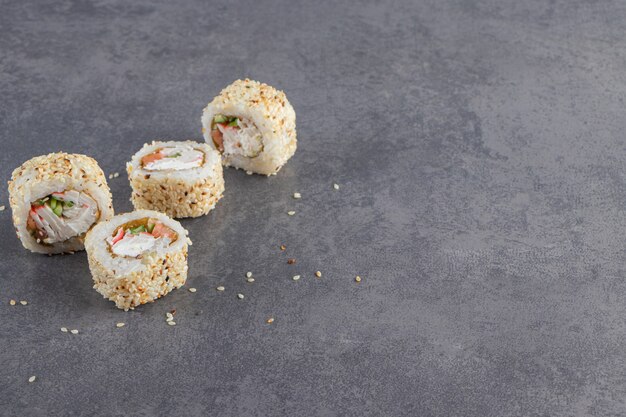 Rollos de sushi decorados con semillas de sésamo sobre fondo de piedra.