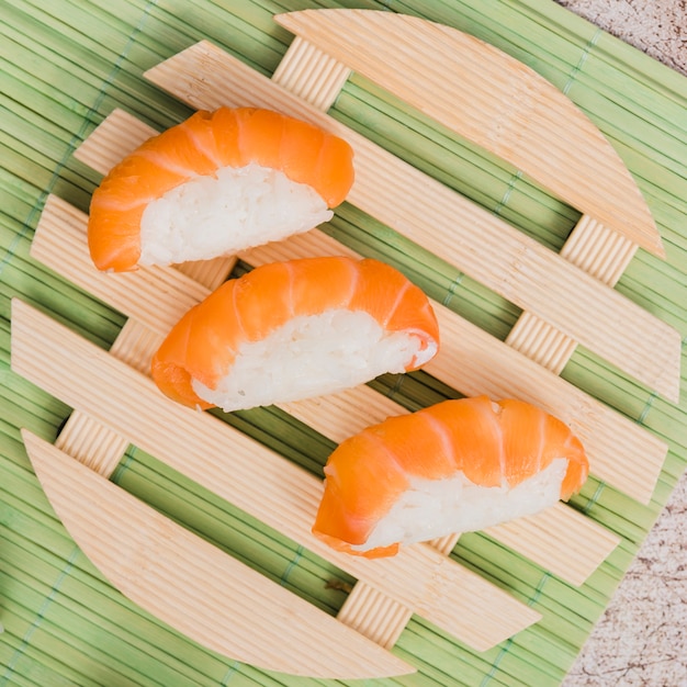 Rollos de sushi de salmón en placa circular de madera sobre mantel verde