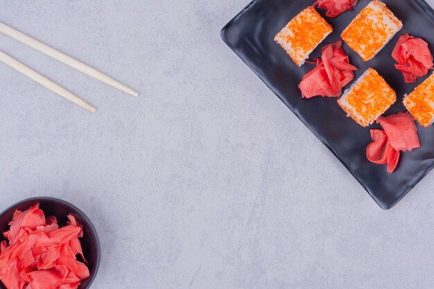 Rollos de sushi con salmón en platos de cerámica negra