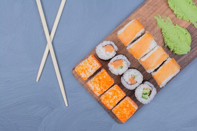 Rollos de sushi con salsa de wasabi en una bandeja de madera