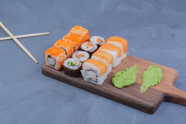 Rollos de sushi con salsa de wasabi en una bandeja de madera