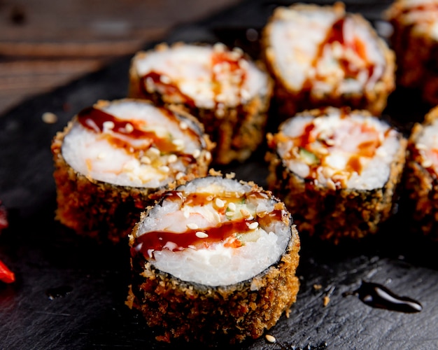 Rollos de sushi servidos con salsa y semillas de sésamo