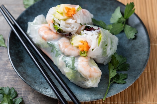 Rolos de primavera vietnamitas con verduras, fideos de arroz y camarones en una mesa de madera