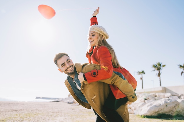 Foto gratuita romántica pareja joven con globo en la costa