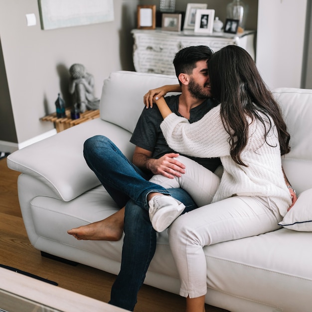 Foto gratuita romántica pareja joven sentada en el sofá blanco amándose