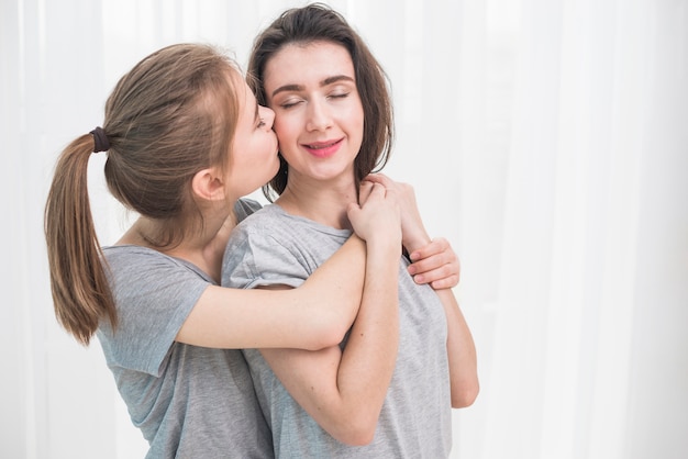 Romántica pareja de lesbianas jóvenes de pie contra la cortina blanca