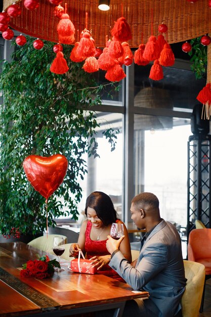 Romántica pareja negra sentada en el restaurante con ropa elegante