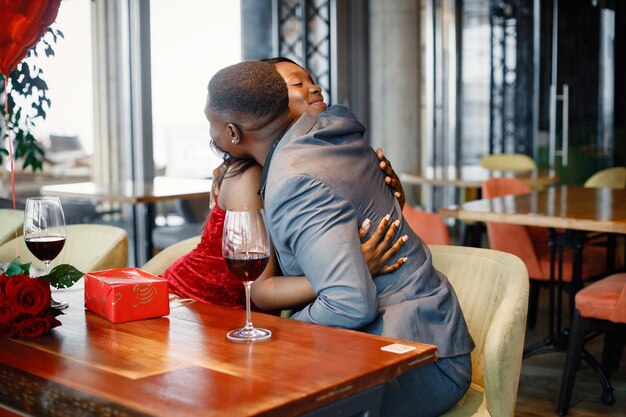 Romántica pareja negra sentada en el restaurante con ropa elegante