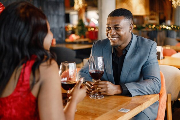 Romántica pareja negra sentada en el restaurante con ropa elegante