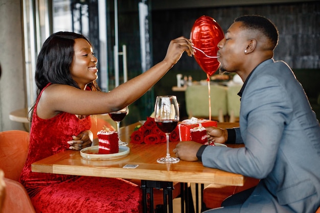 Romántica pareja negra sentada en el restaurante con ropa elegante