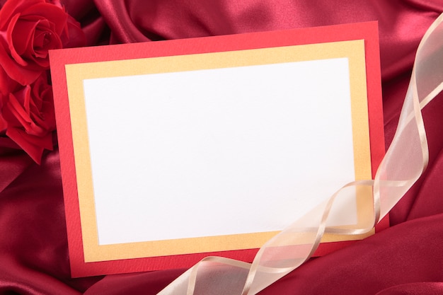 Romántica tarjeta de san valentín con una cinta sobre seda roja 