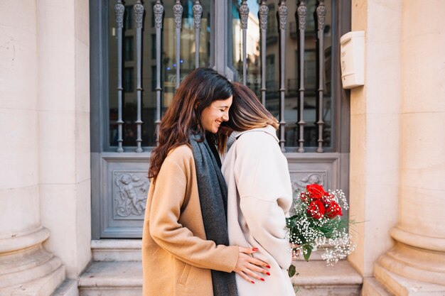 Románticas novias jóvenes con flores en la calle