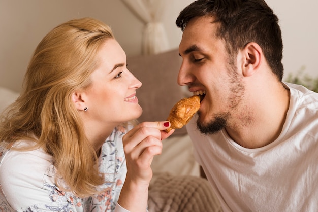 Romántico joven hombre y mujer compartiendo un croissant