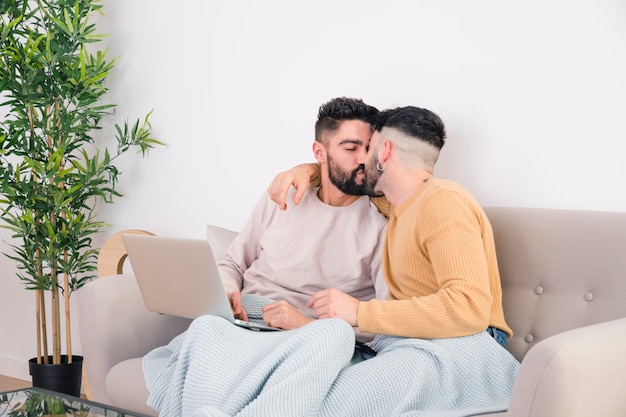 Foto gratuita romántico joven pareja gay sentado en el sofá besándose