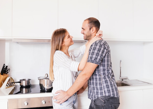 Romántico joven pareja de pie en la cocina mirando mutuamente