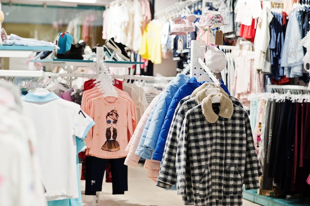 La ropa brillante de los niños cuelga en la exhibición en la sección de niñas de la tienda de ropa para bebés
