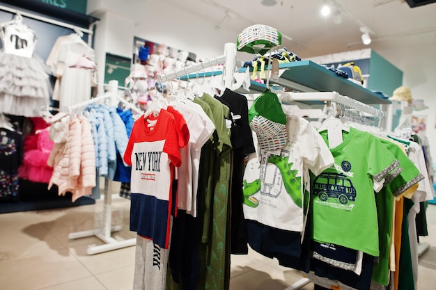 La ropa brillante de los niños cuelga en la exhibición en la sección de niños de la tienda de ropa para bebés