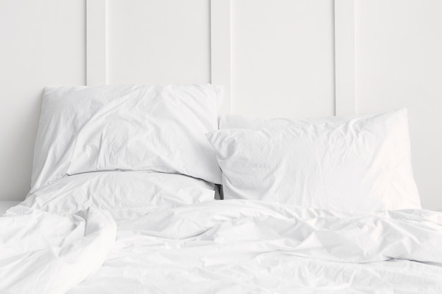 Ropa de cama blanca en una cama en un dormitorio blanco