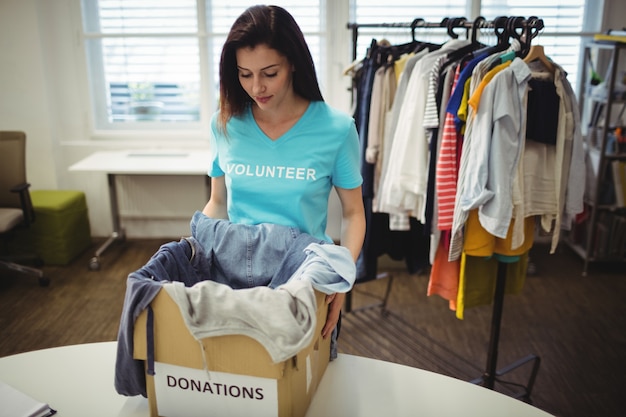 Ropa femenina que sostiene voluntarios en caja de donación