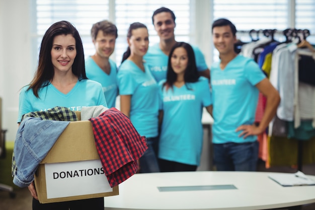 Ropa femenina que sostiene voluntarios en caja de donación