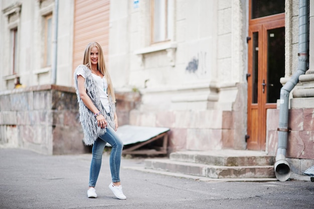 Ropa de mujer rubia con estilo en jeans y chica sin mangas con camisa blanca contra la calle Retrato de modelo urbano de moda