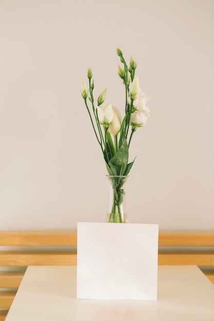 Rosa flores en jarrón con papel en blanco.