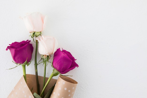 Rosa flores en paquete de papel en mesa blanca