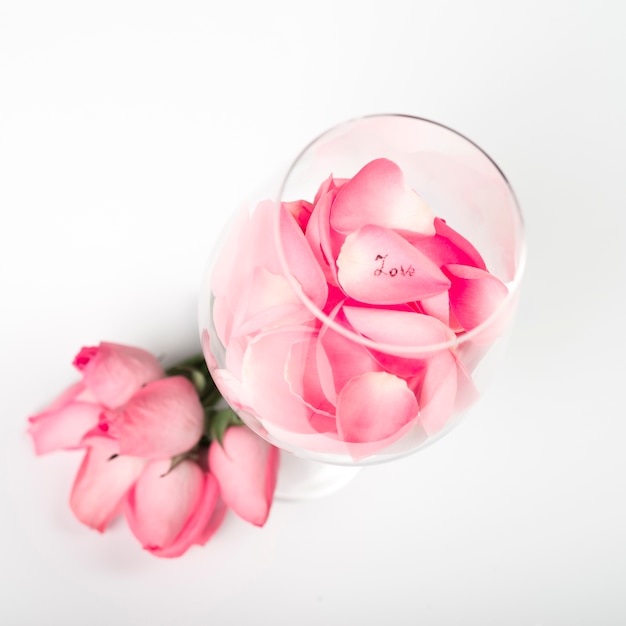 Rosa pétalos de rosas en vidrio en mesa