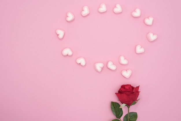 Foto gratuita rosa roja con corazones de discurso de burbuja sobre fondo de papel de color rosa