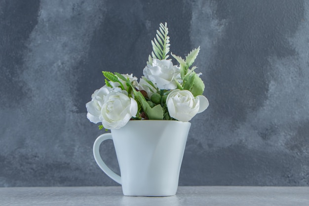 Rosas blancas en una taza blanca, sobre fondo blanco. Foto de alta calidad