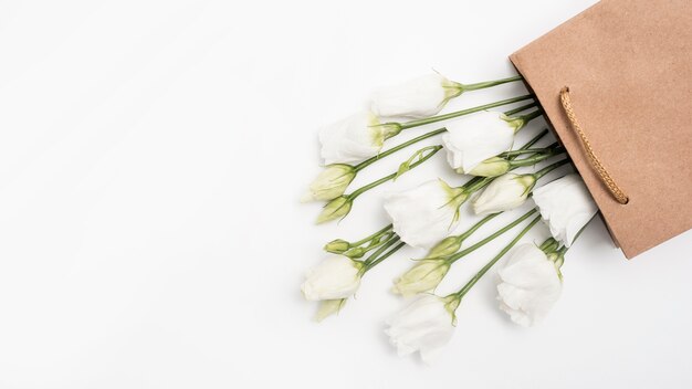 Rosas blancas en una vista superior de bolsa de regalo de papel