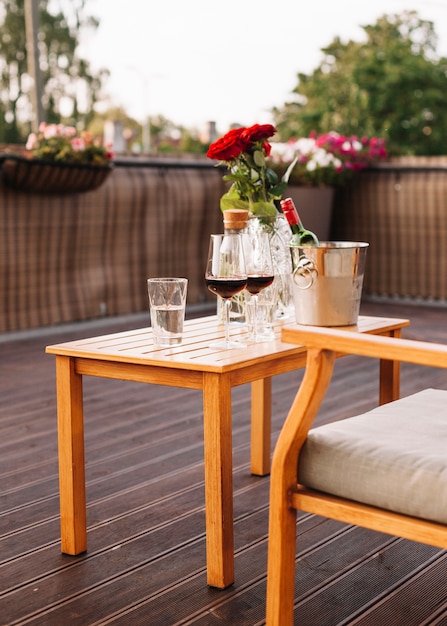 Rosas; Copa de vino y cubo de hielo en la mesa de madera en el restaurante