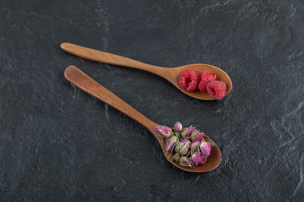 Rosas y frambuesas en ciernes en cucharas de madera.