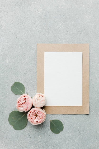 Foto gratuita rosas y hojas planas con papeles en blanco y marco
